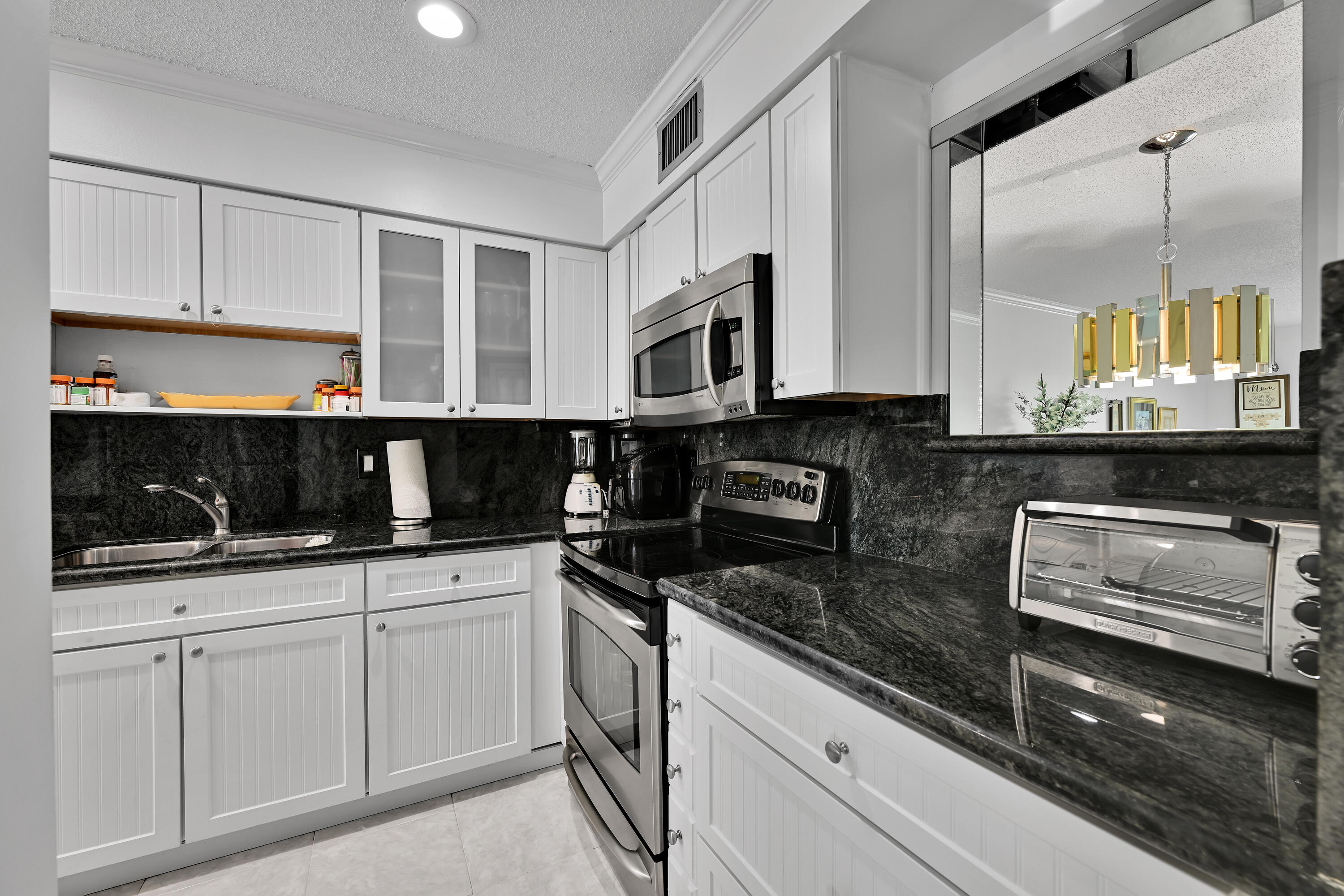 13791 Flora Place, Unit D Delray Beach, FL 33484 - Photo 12 of 24 a kitchen with granite countertop white cabinets and black appliances