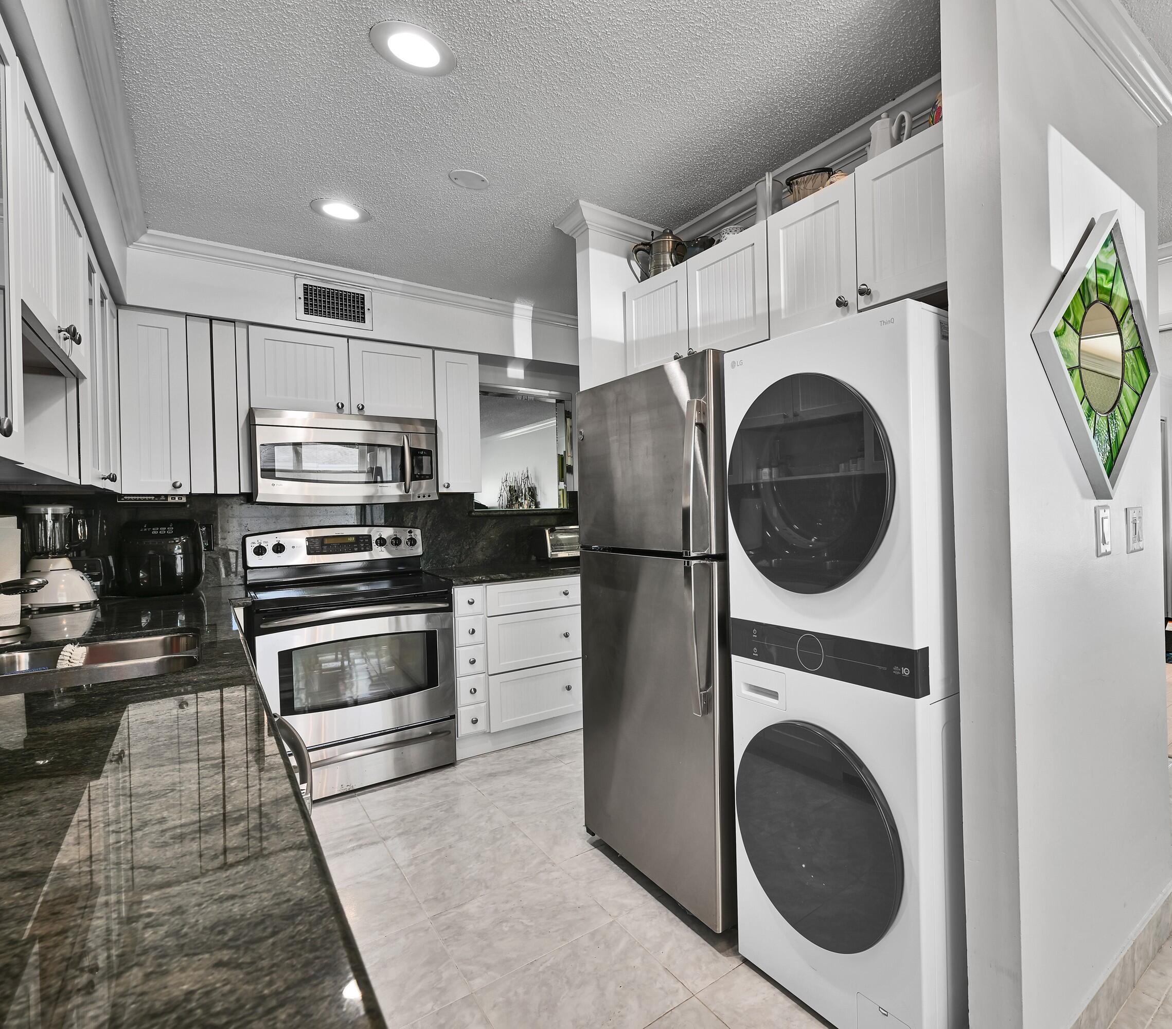 13791 Flora Place, Unit D Delray Beach, FL 33484 - Photo 14 of 24 a kitchen with stainless steel appliances kitchen island wooden cabinets and stove top oven