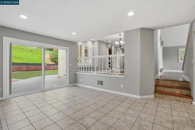 a view of an empty room with wooden floor and chandelier