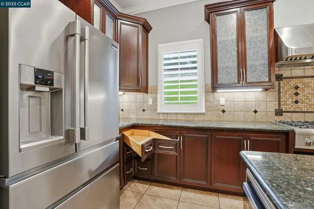 a kitchen with stainless steel appliances granite countertop a sink and a refrigerator