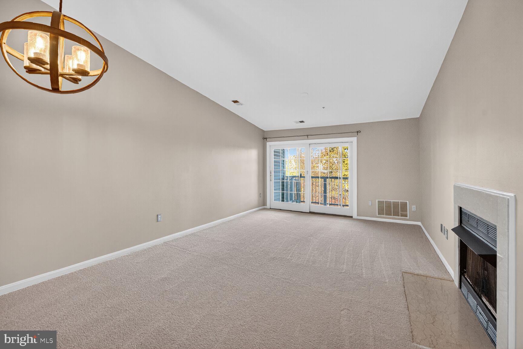 44084 Natalie Terrace, Unit 301 Ashburn, VA 20147 - Photo 2 of 15 an empty room with a fireplace and a window