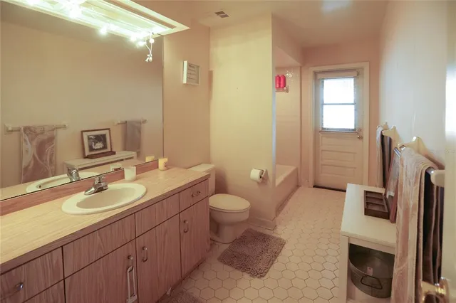 a bathroom with a granite countertop toilet sink and mirror