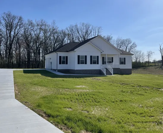 a front view of a house with a garden and trees