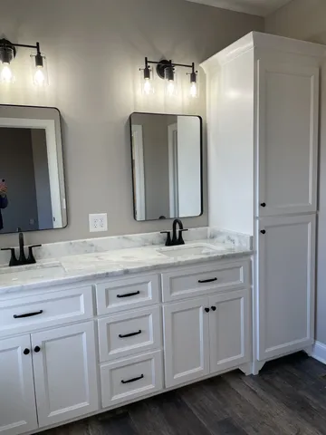 a bathroom with double vanity sink a two mirror a window and a bathtub