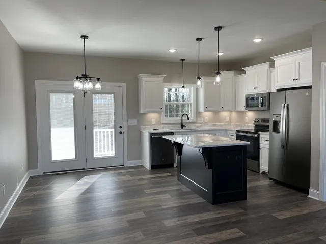 a kitchen with stainless steel appliances granite countertop a stove a refrigerator a sink a center island and wooden floor