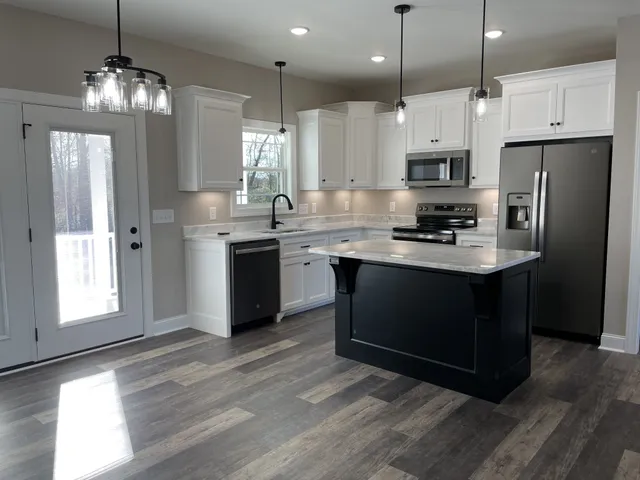 a kitchen with a white center island a sink stainless steel appliances and cabinets