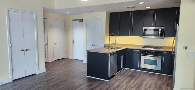 a kitchen with stainless steel appliances granite countertop a stove a sink and a refrigerator with wooden floors