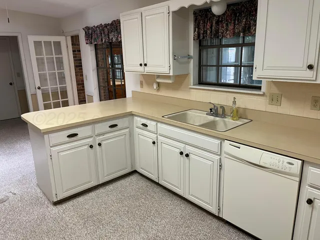 a kitchen with white cabinets and sink