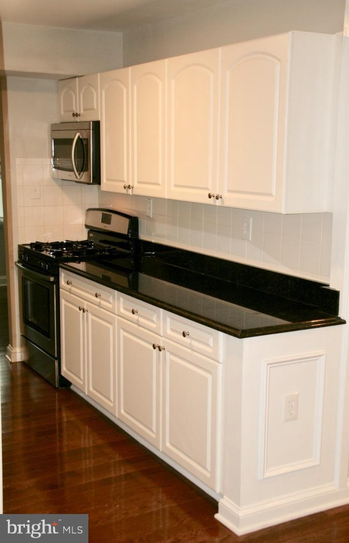 581 Summit Hall Road Gaithersburg, MD 20877 - Photo 9 of 22 a kitchen with granite countertop white cabinets and black appliances