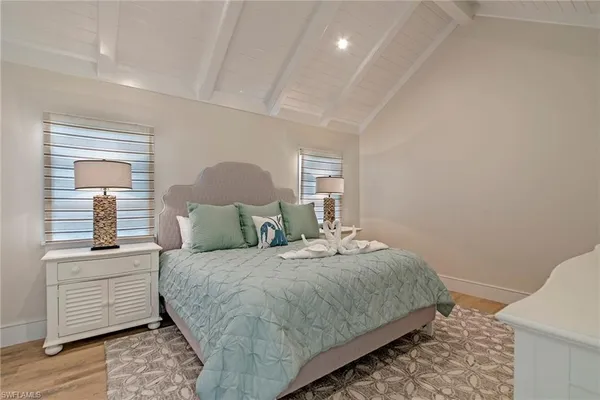 a bedroom with a large bed and wooden floor