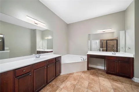 a spacious bathroom with a sink double vanity granite tub and a mirror