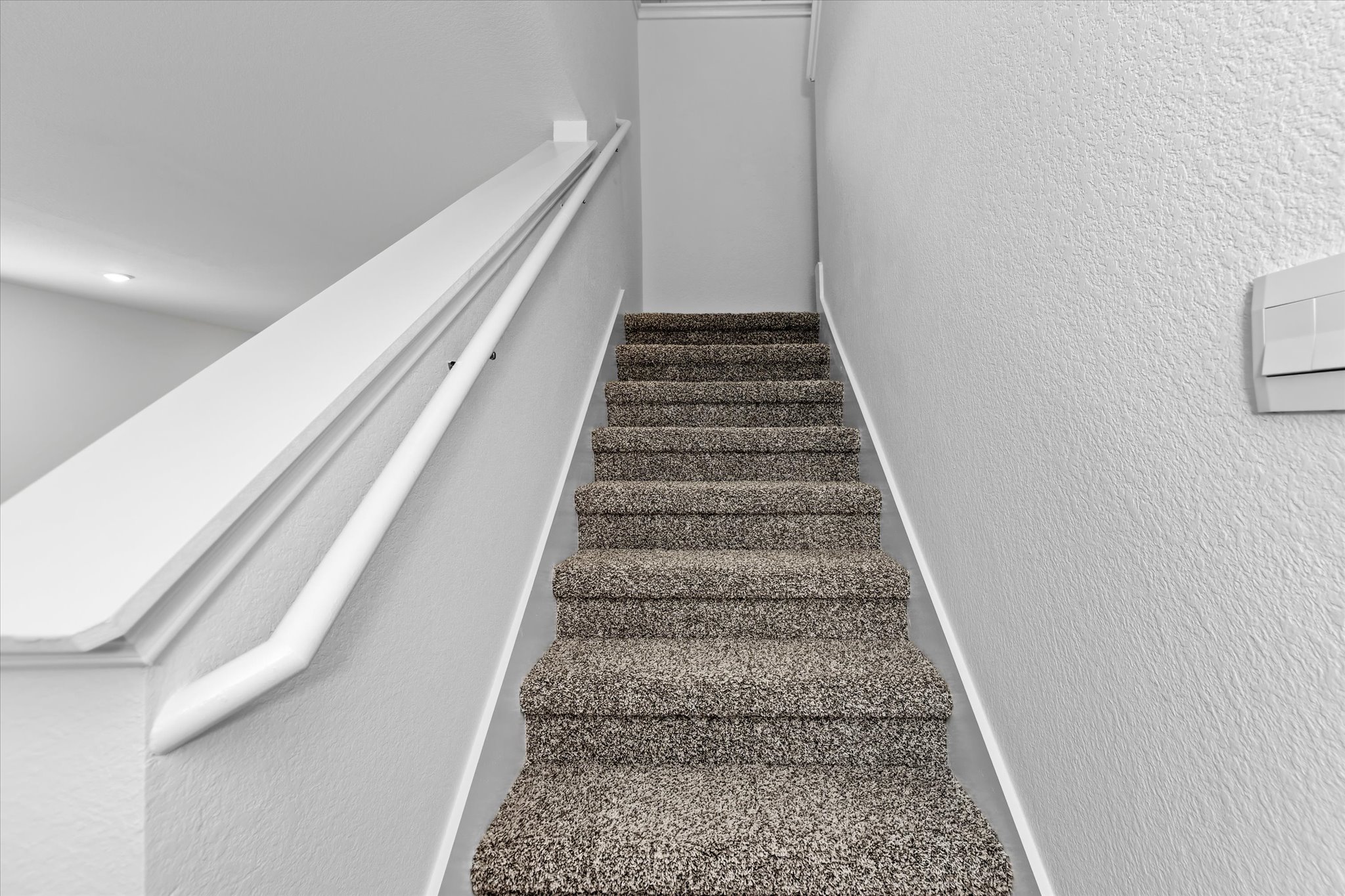 456 Sandringham Loop Kyle, TX 78640 - Photo 10 of 40 A well-maintained carpeted staircase with a crisp white handrail awaits, leading to upper levels.