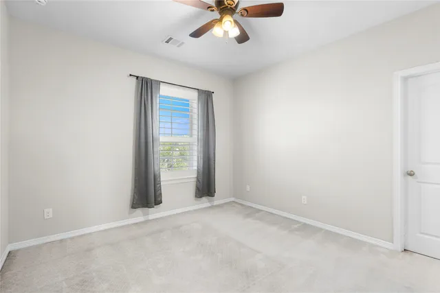 an empty room with a window and a fan