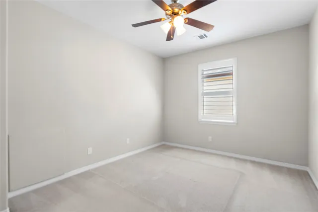 an empty room with a window and a fan