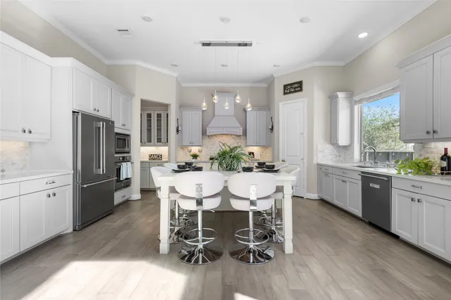 a kitchen with stainless steel appliances granite countertop a dining table chairs refrigerator and cabinets