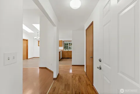 a view of a hallway with wooden floor windows and a bathroom