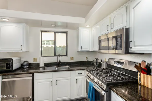 a kitchen with granite countertop a sink a stove and cabinets