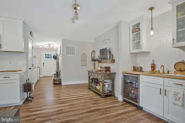 a kitchen with stainless steel appliances a stove top oven a sink a refrigerator white cabinets and wooden floor