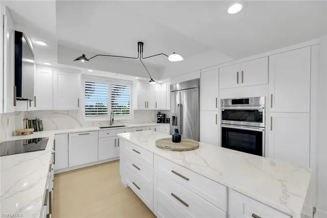 a kitchen with a refrigerator a stove a sink and white cabinets