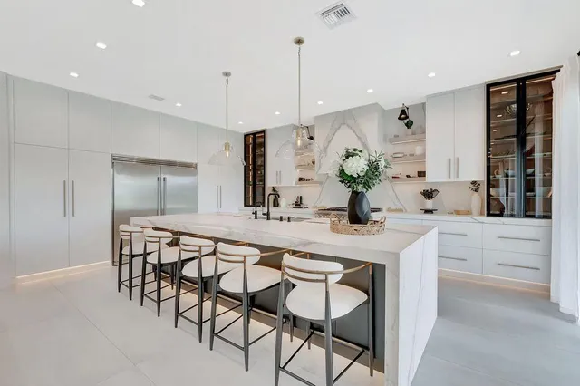 a kitchen with white cabinets and chairs