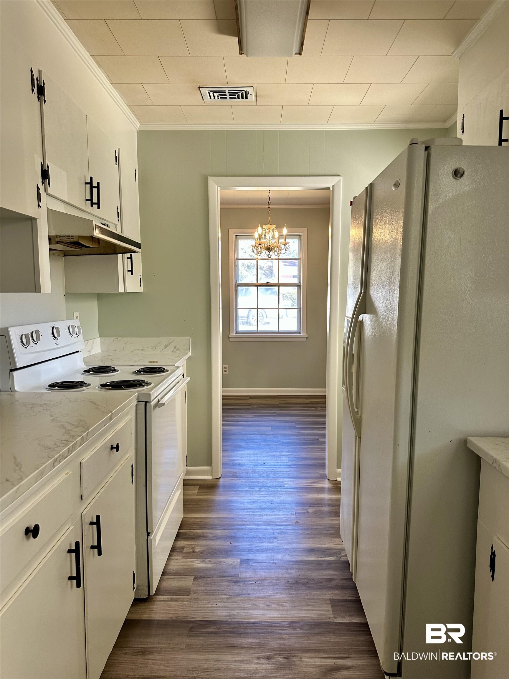 103 Avalon Street Brewton, AL 36426 - Photo 5 of 14 Kitchen featuring white cabinetry, dark hardwood / wood-style floors, a chandelier, white appliances, and decorative light fixtures