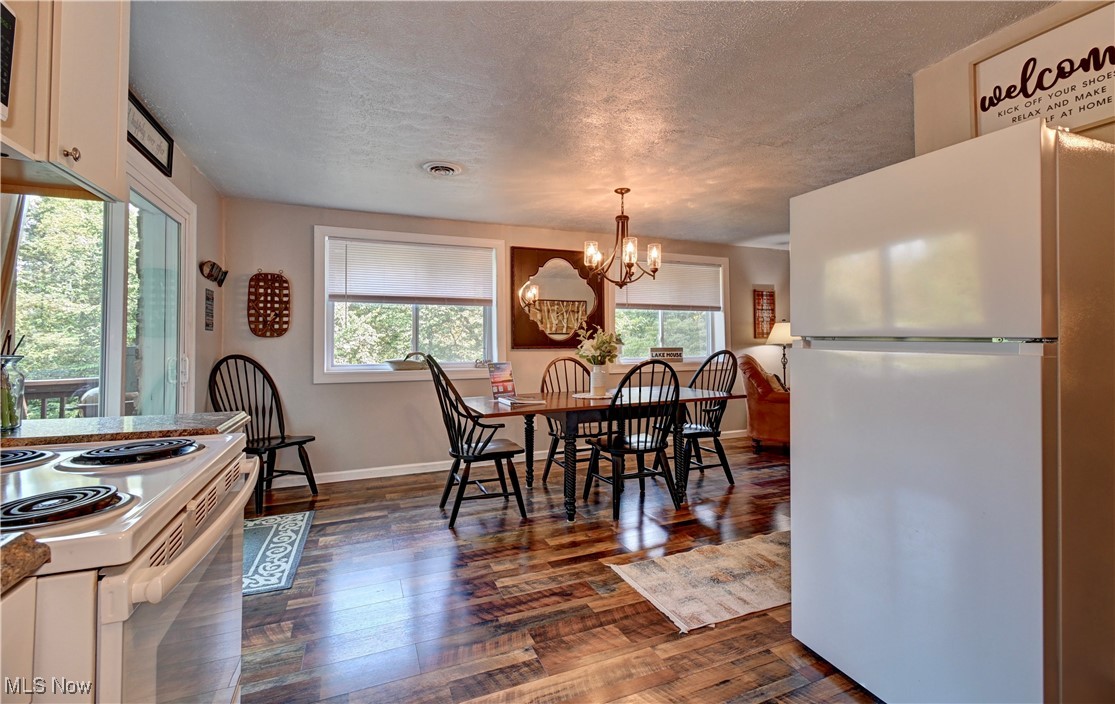 2227 Elk Road Southwest Carrollton, OH 44615 - Photo 29 of 40 Dining room with dark wood-style flooring, a textured ceiling, and a chandelier
