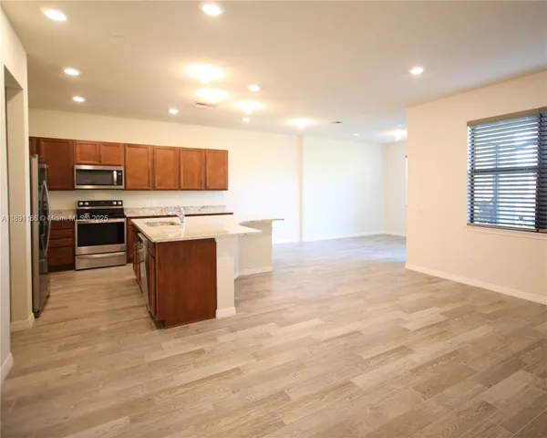 a kitchen with stainless steel appliances granite countertop a stove top oven a sink dishwasher and a refrigerator with wooden floor