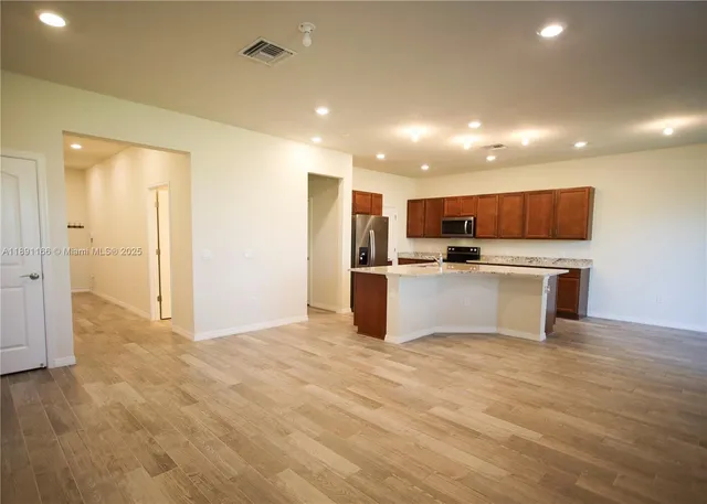a large kitchen with kitchen island granite countertop a sink and cabinets