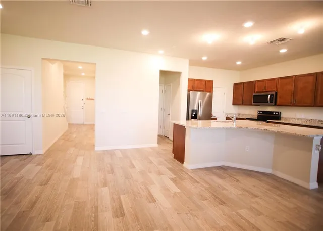 a large kitchen with stainless steel appliances kitchen island a large counter top and a wooden floors