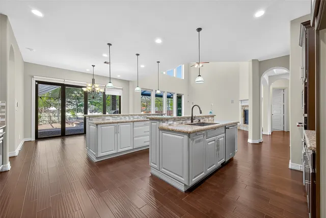 a dining room with wooden floor a chandelier a glass table and chairs