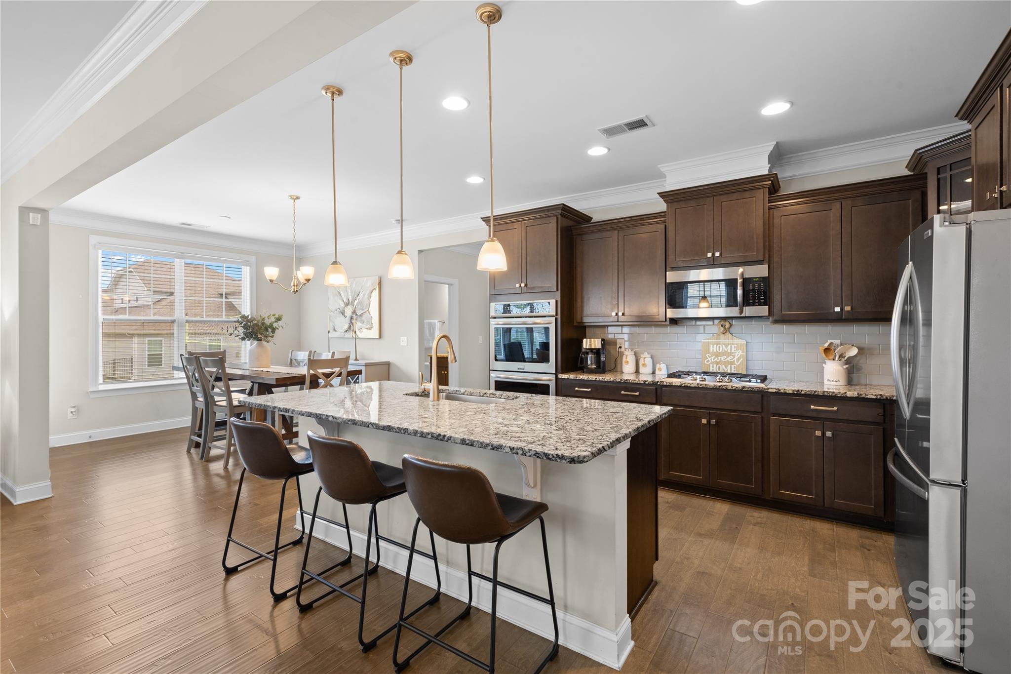 7035 Bareland Road Fort Mill, SC 29707 - Photo 11 of 47 a kitchen with stainless steel appliances granite countertop a stove top oven a sink a refrigerator and white cabinets with wooden floor