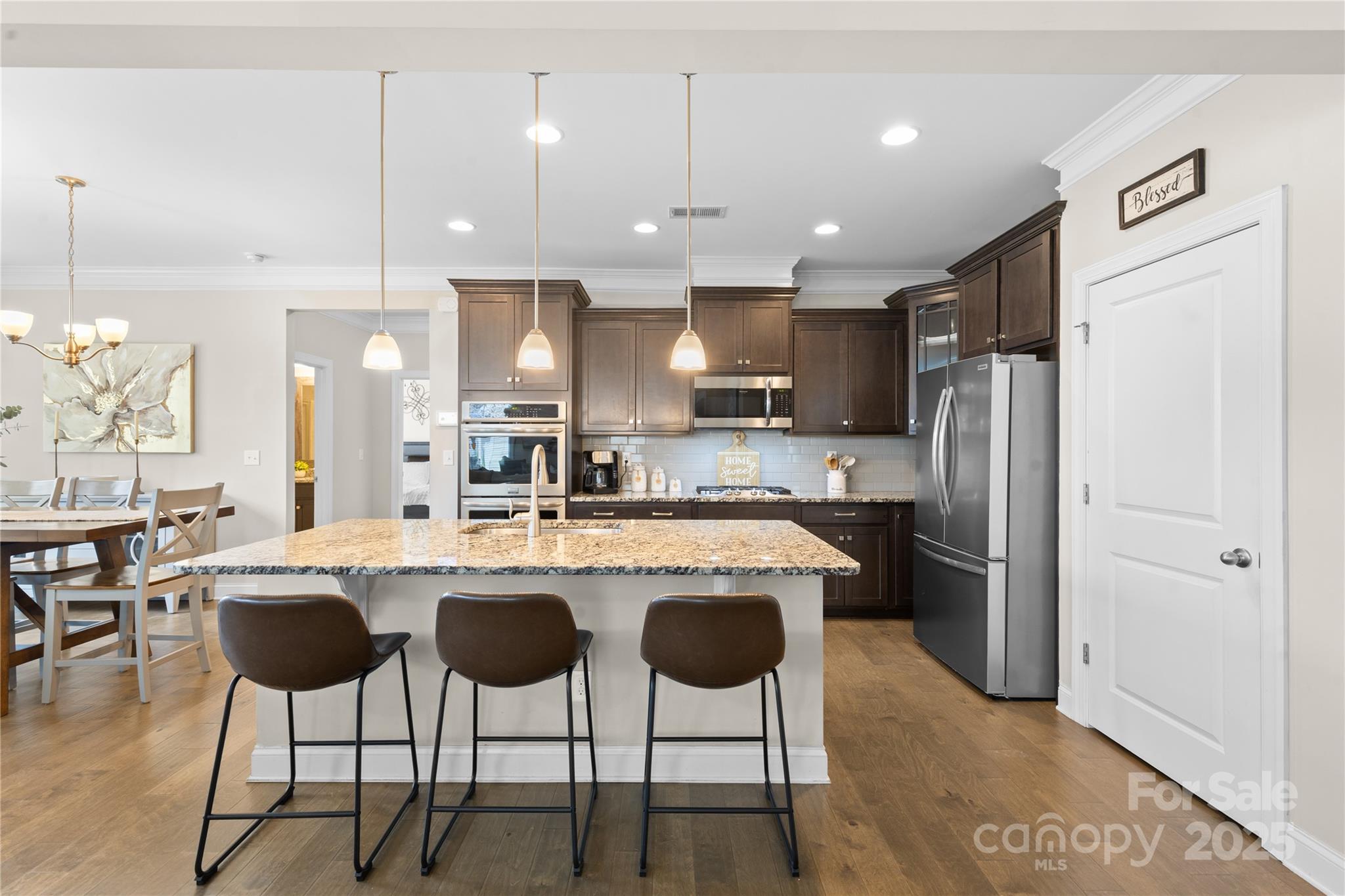 7035 Bareland Road Fort Mill, SC 29707 - Photo 13 of 47 a kitchen with stainless steel appliances kitchen island granite countertop a dining table chairs refrigerator sink and cabinets