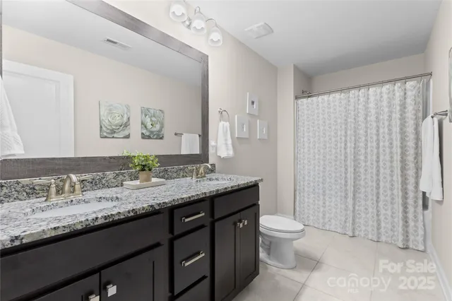 a bathroom with a granite countertop sink a toilet and a mirror