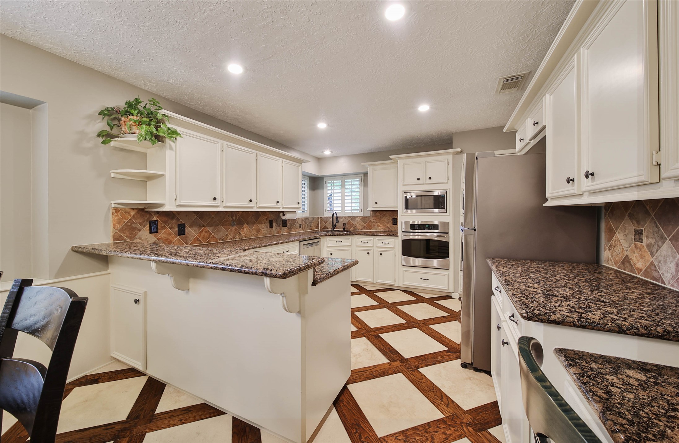 17007 Windrow Drive Spring, TX 77379 - Photo 14 of 46 a kitchen with stainless steel appliances granite countertop a stove top oven a refrigerator a sink and white cabinets with wooden floor