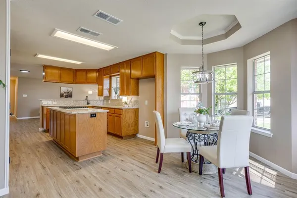 a kitchen with stainless steel appliances kitchen island granite countertop a table chairs and a refrigerator