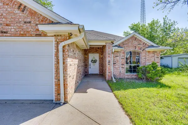 a view of a house with brick walls plants and large tree