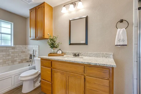 a bathroom with a granite countertop sink toilet and mirror