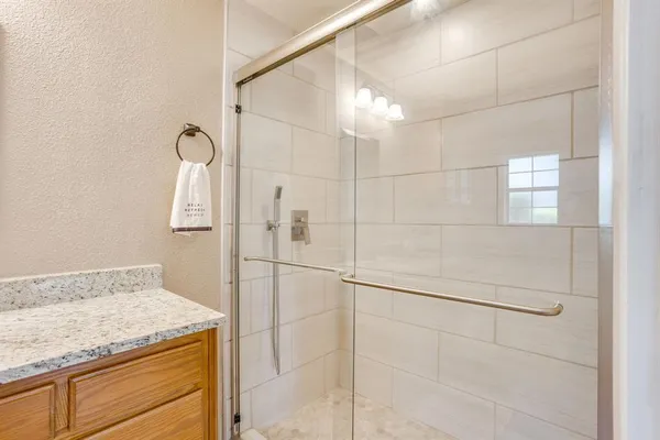 a bathroom with a granite countertop sink a mirror and shower