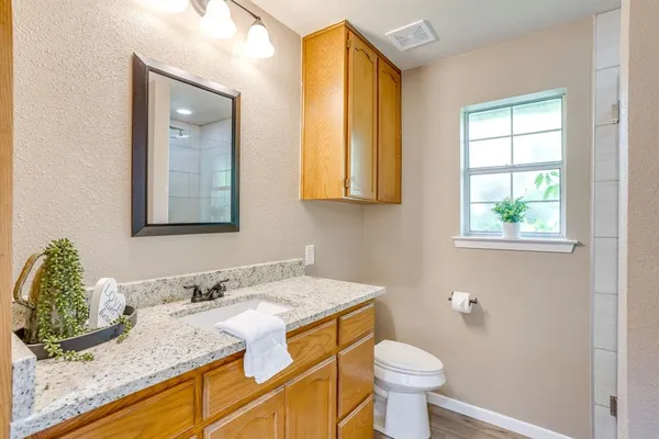 a bathroom with a granite countertop sink toilet and mirror