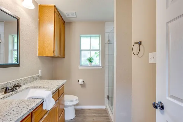 a bathroom with a granite countertop sink toilet and mirror