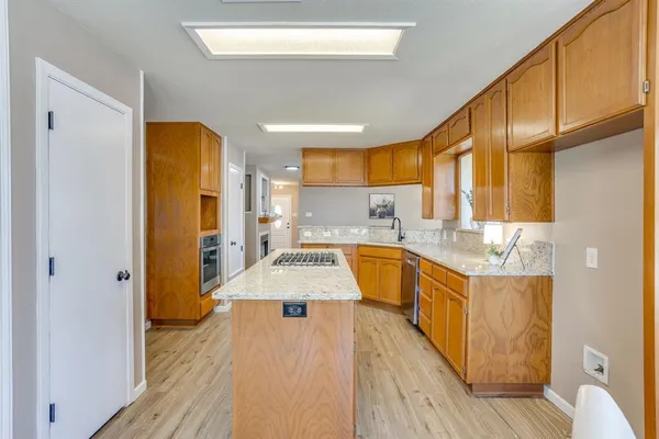 a large kitchen with a sink a counter top space and stainless steel appliances