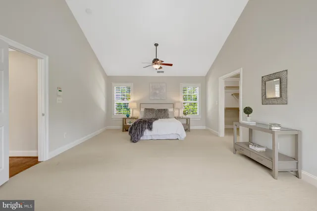 a spacious bedroom with a bed a couch and windows