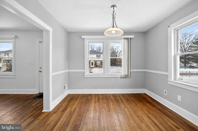a view of empty room with wooden floor and window