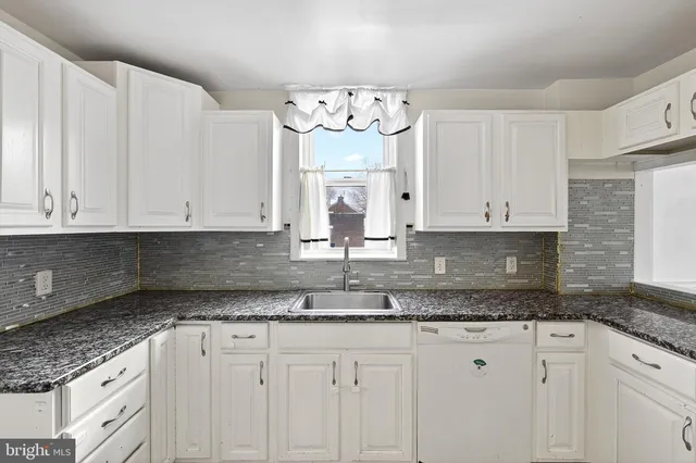 a kitchen with granite countertop white cabinets white stainless steel appliances and a window