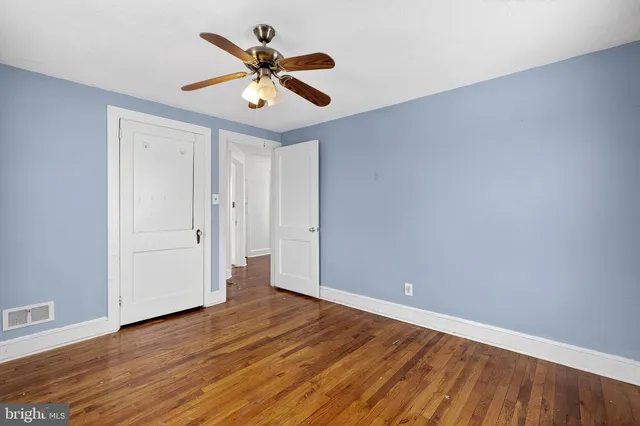 an empty room with wooden floor and a ceiling fan
