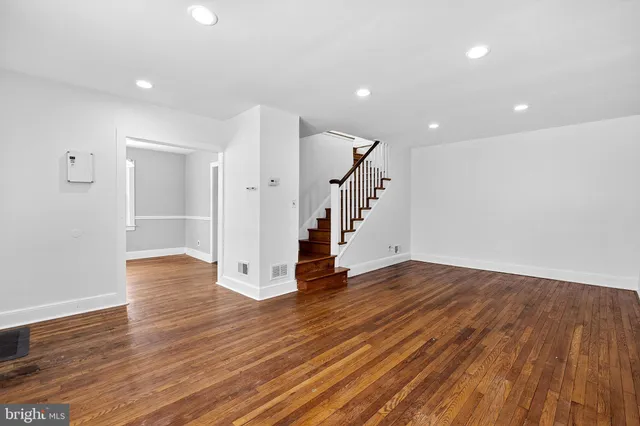 a view of an empty room with wooden floor and stairs