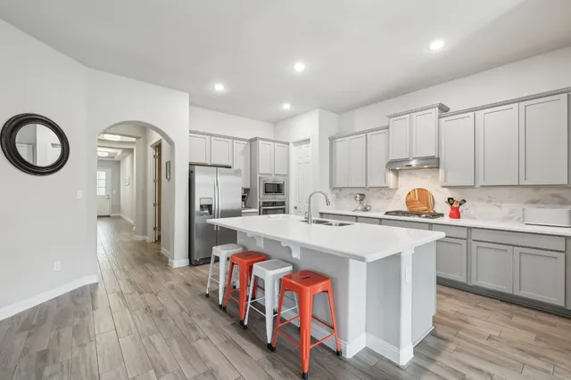 a kitchen with a sink a stove a refrigerator and white cabinets with wooden floor
