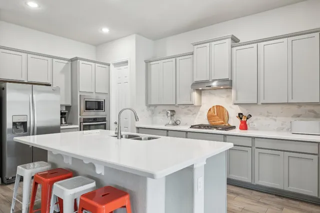 a kitchen with stainless steel appliances a sink a stove a refrigerator cabinets and a counter top space