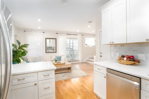 a kitchen with a sink dishwasher stove and white cabinets with wooden floor