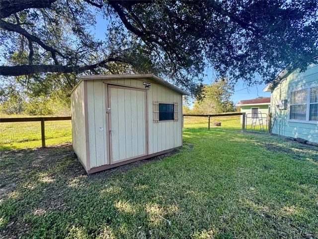 a view of backyard with a barn and large trees